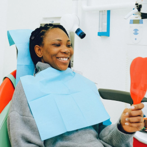 Patient smiling and looking at her teeth after dental treatment